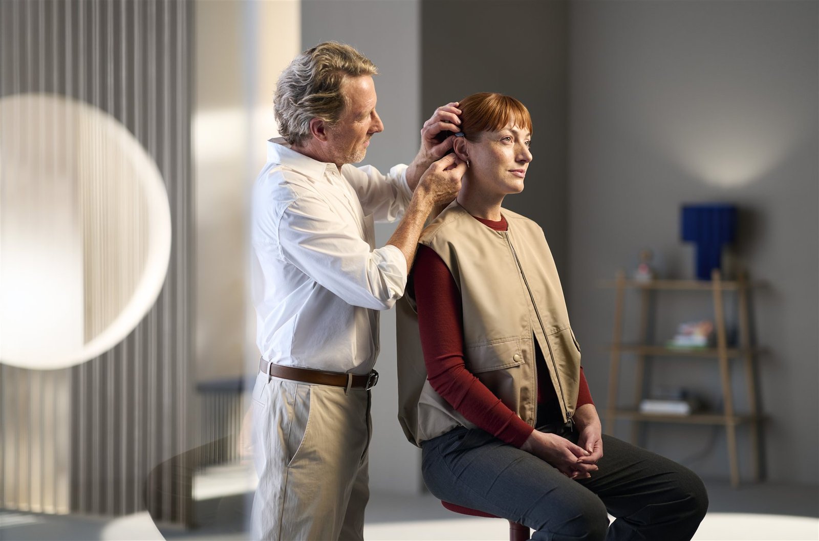 Audioprothésiste ajustant un appareil auditif à l’oreille d’une patiente